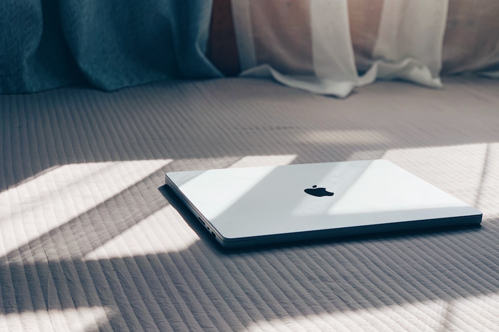 an apple laptop sitting on a bed in a room