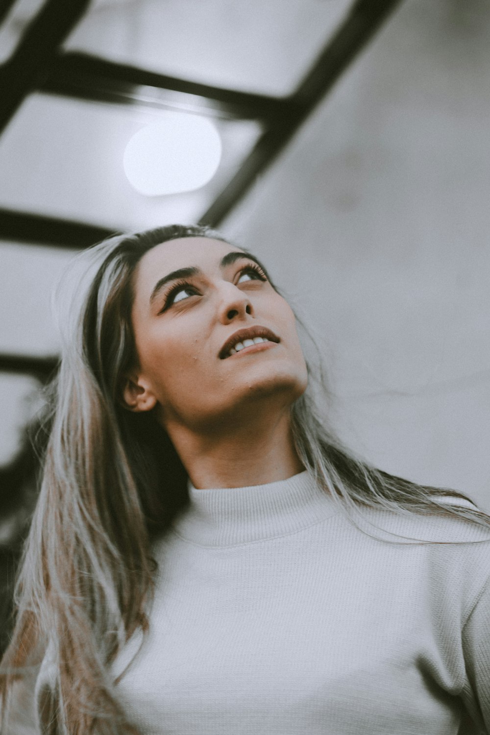 a woman in a white sweater looking up