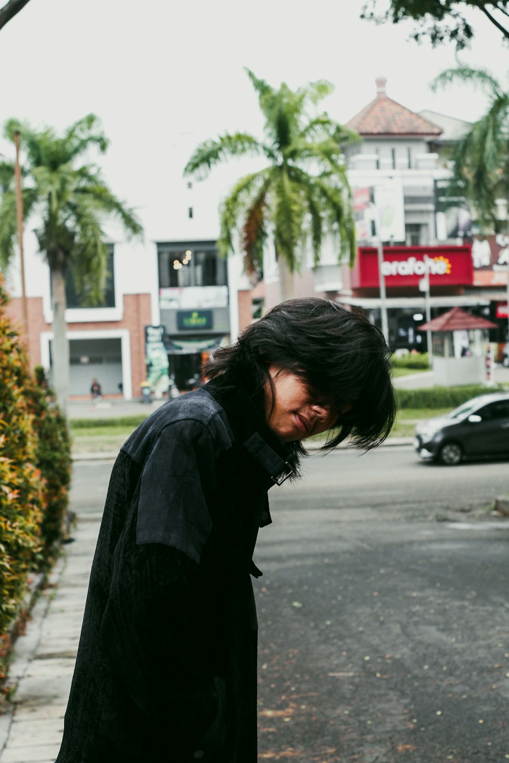 a man standing on the side of a road holding a skateboard