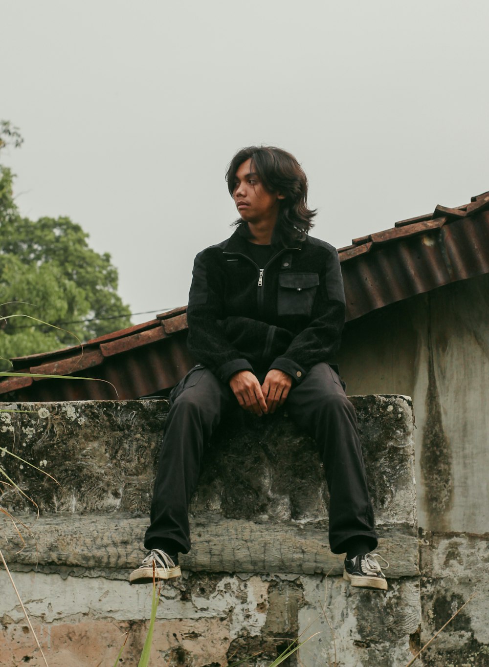 a man sitting on top of a stone wall