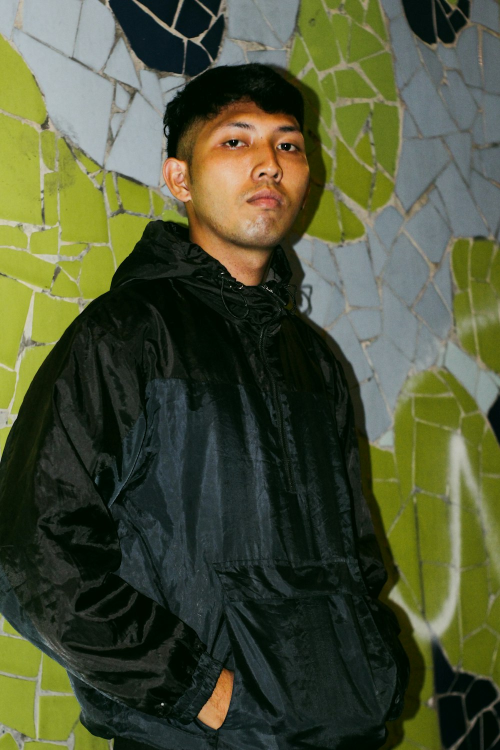 a man standing in front of a mosaic wall