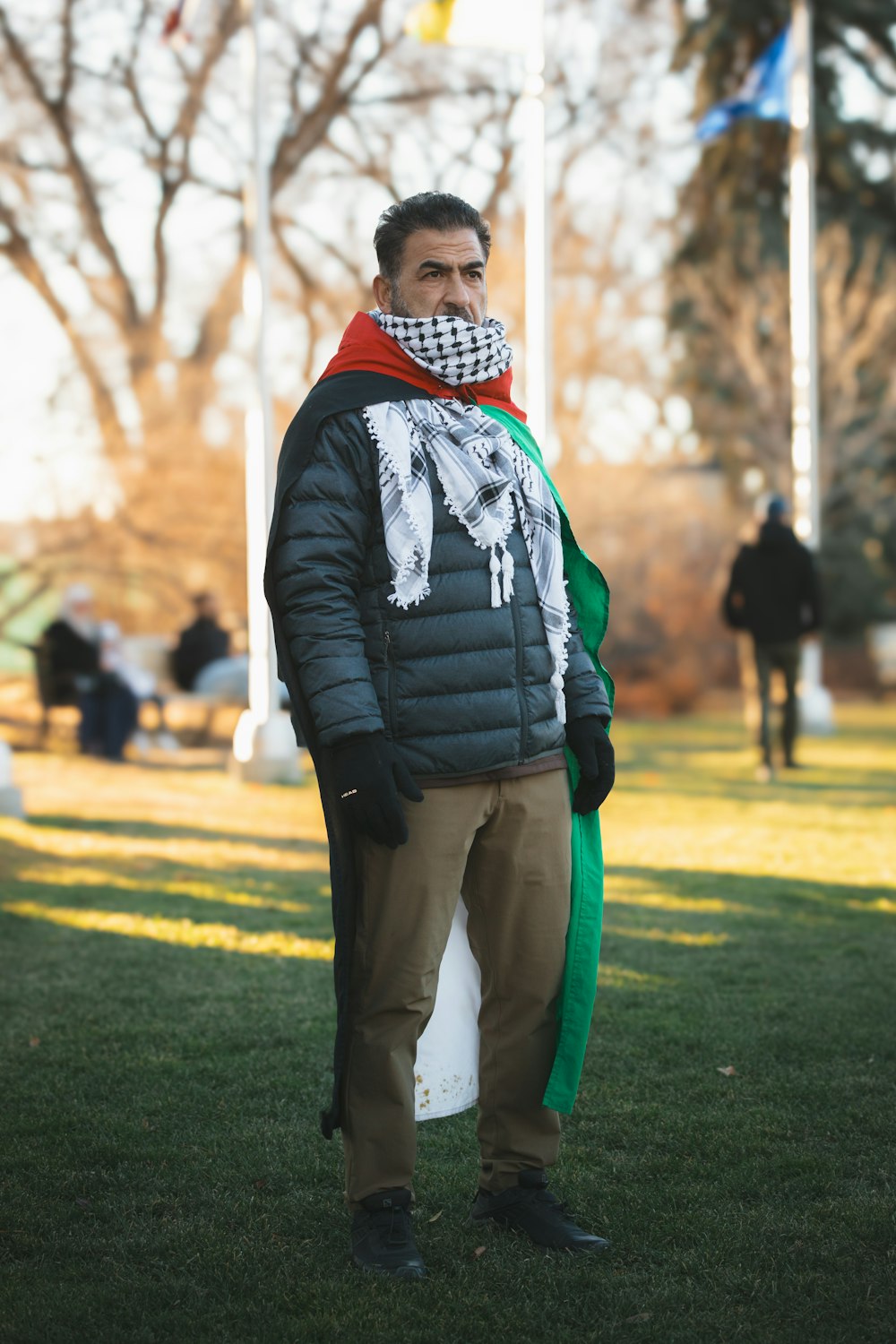 a man standing in the grass with a scarf around his neck