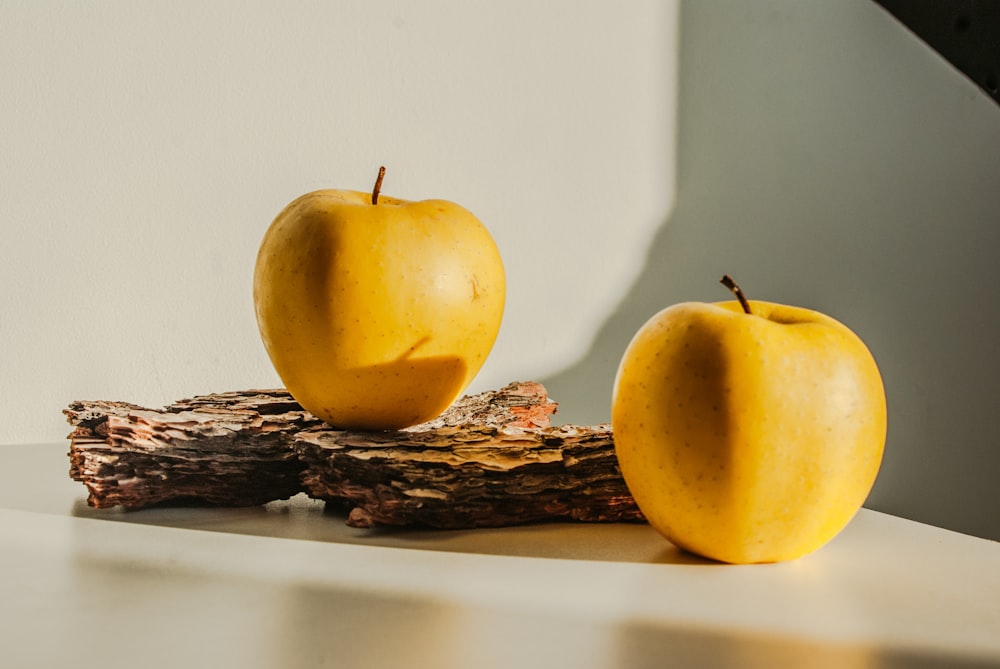 a couple of yellow apples sitting on top of a table