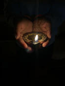 Hands holding a handcrafted temple tool glowing gently in natural light.