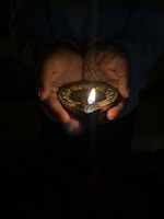 Close-up of hands holding a glowing diya, representing purity and divine grace.