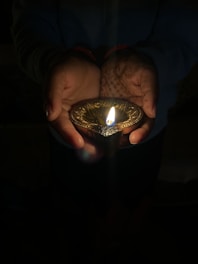 Hands holding a glowing light, representing nurturing dharma within the family.
