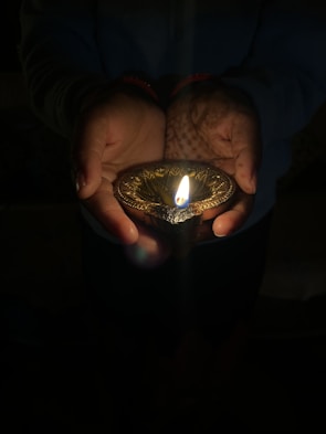 Close-up of hands holding a glowing diya, representing purity and divine grace.