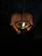 Close-up of a hand holding the glowing Maha Mrityunjaya Tabij against a softly lit temple backdrop.