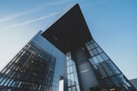 Tall, modern skyscrapers displaying sleek glass facades rise against a clear blue sky, creating an impressive urban landscape. One building prominently features the Hyatt logo.