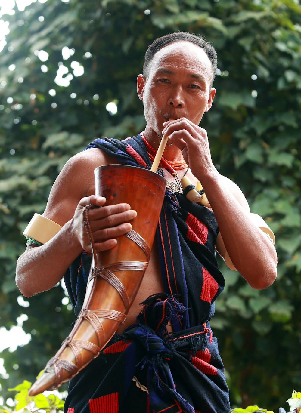 a man is playing a flute in front of a tree