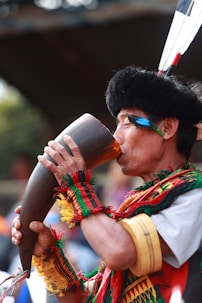 a man in a native american costume drinking from a cup