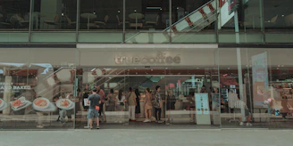 A modern drive thru coffee shop exterior with cars lining up at the ordering window during golden hour.