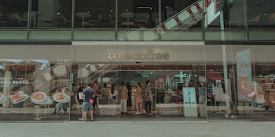 A modern drive thru coffee shop exterior with cars lining up at the ordering window during golden hour.