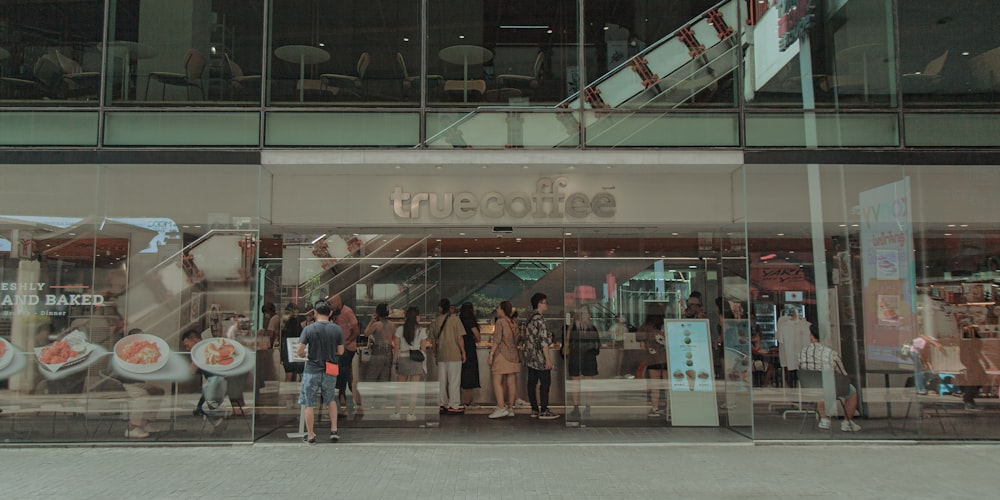 a group of people standing outside of a coffee shop