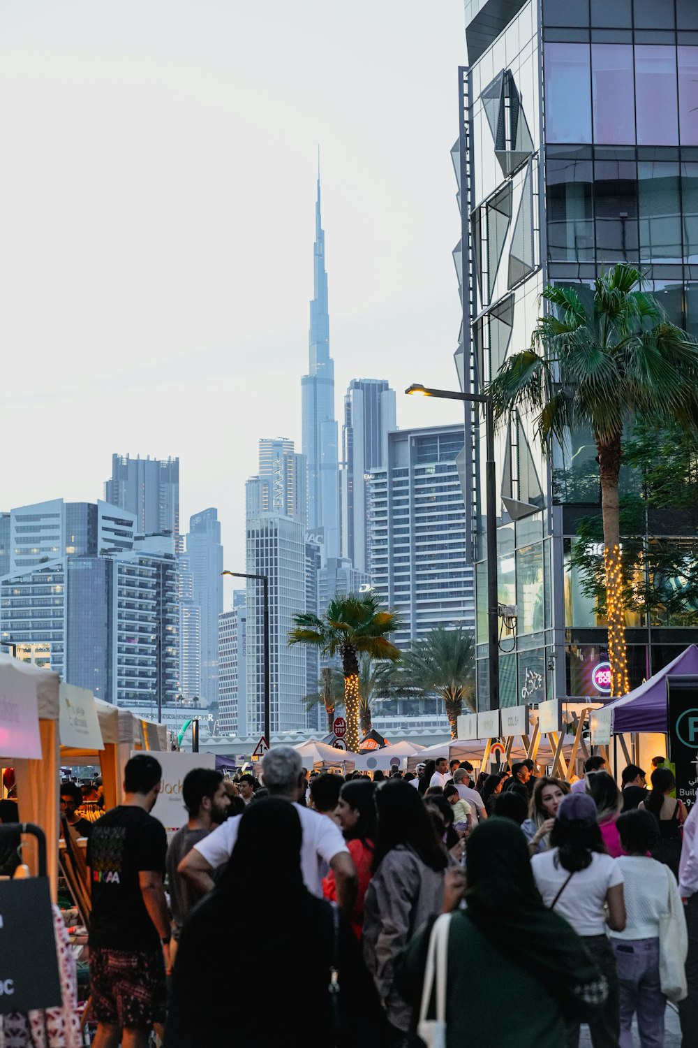 a crowd of people walking down a street next to tall buildings