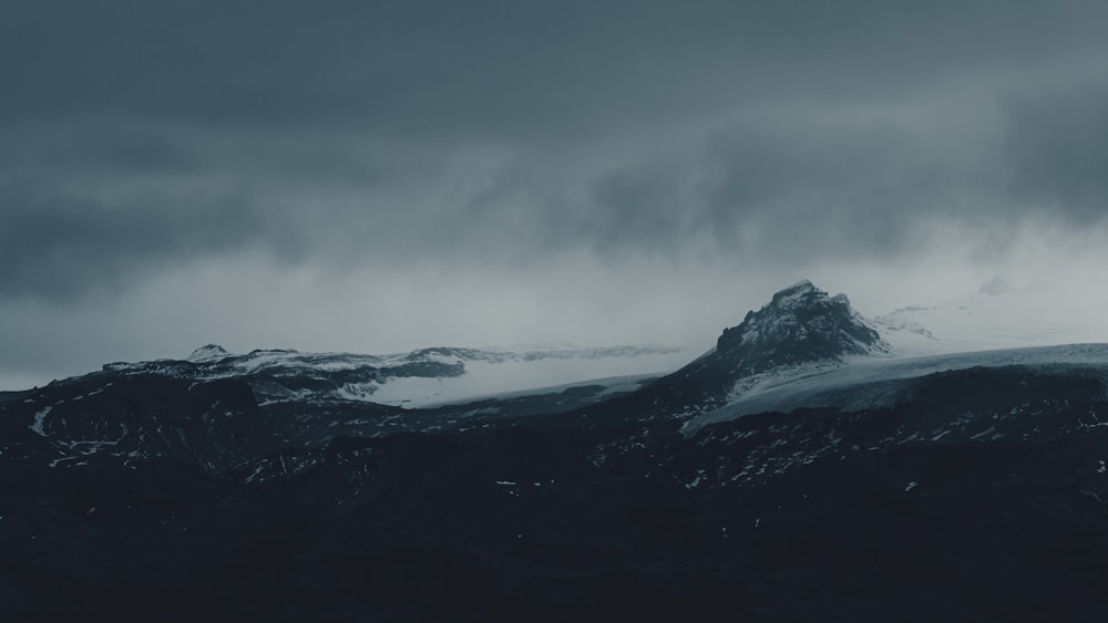 a mountain covered in snow under a cloudy sky