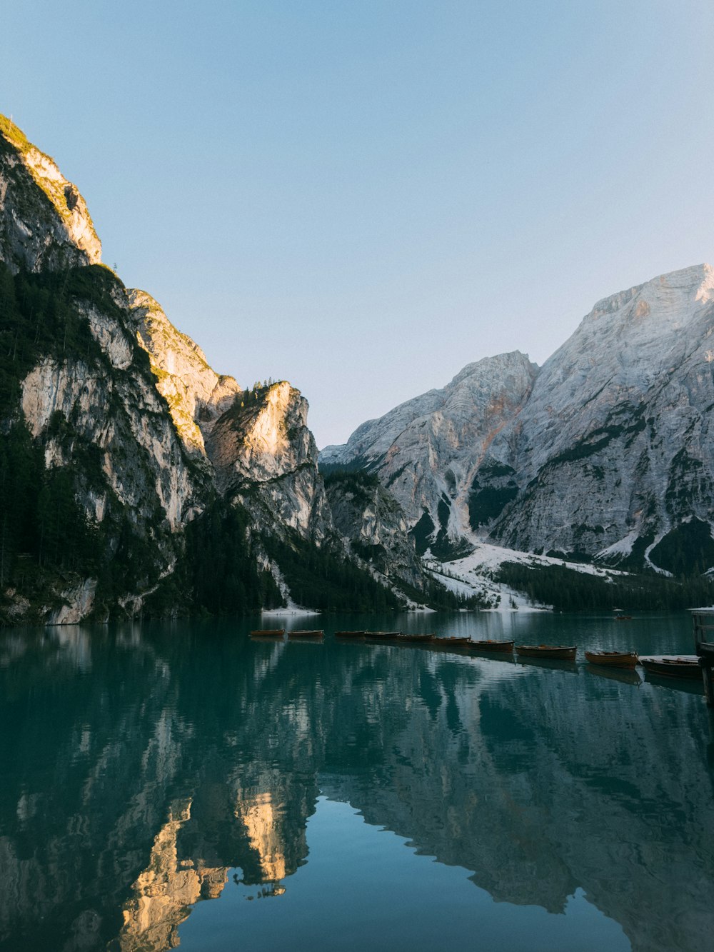 a lake surrounded by mountains with a clear sky