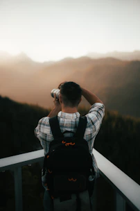 A backpacker taking photos of a stunning mountain landscape at sunrise.