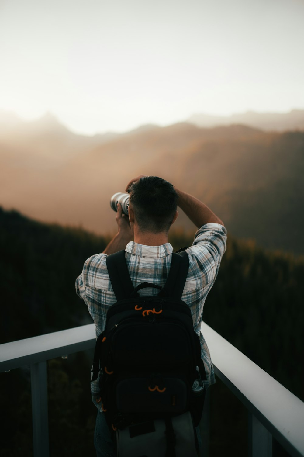 a man standing on a balcony looking at the mountains