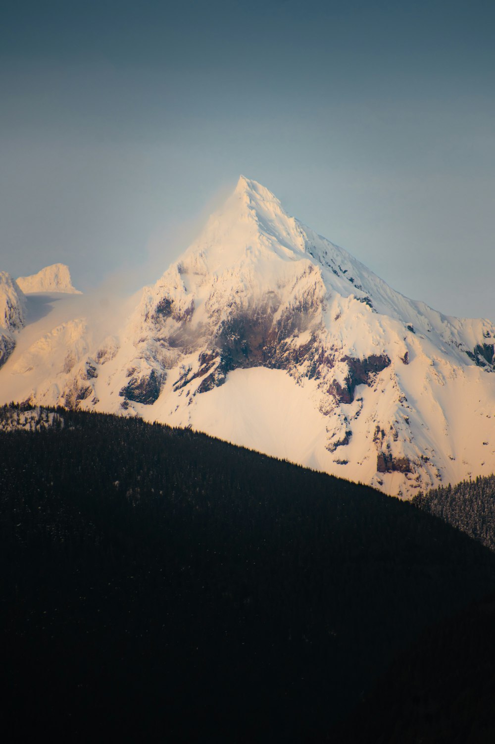 a mountain covered in snow with a sky background