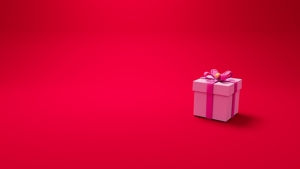 a pink gift box with a bow on a red background