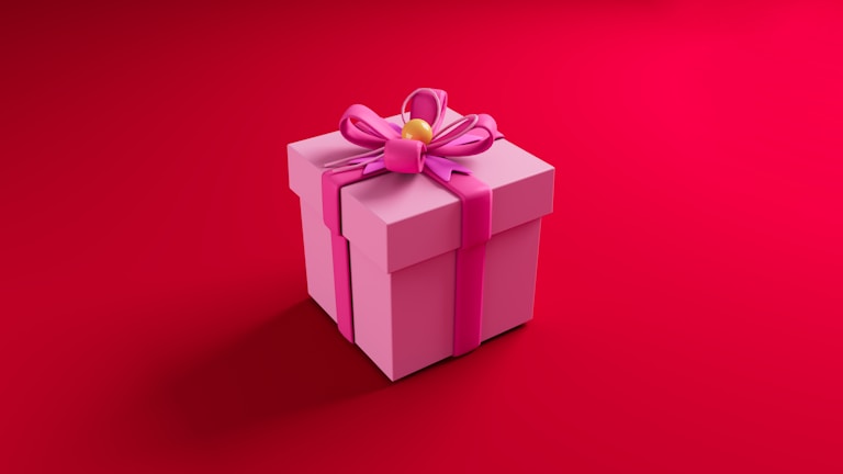 A pink gift box with a large pink ribbon and bow on top, set against a vibrant red background. The box has a yellow decorative center in the middle of the bow.