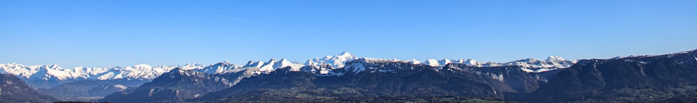 a view of a mountain range with a plane flying in the sky