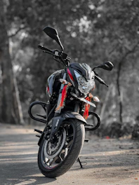 A sleek black motorcycle with gold accents parked on a coastal road at sunset, symbolizing premium escort services.