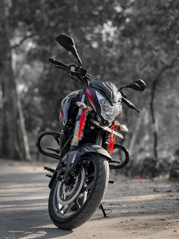 A sleek black motorcycle with gold accents parked on a coastal road at sunset, symbolizing premium escort services.