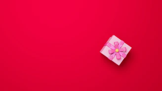 Close-up of a pastel pink ribbon with elegant Arabic calligraphy embroidery on a gift box.