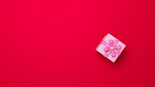 Close-up of a pastel pink ribbon with elegant Arabic calligraphy embroidery on a gift box.
