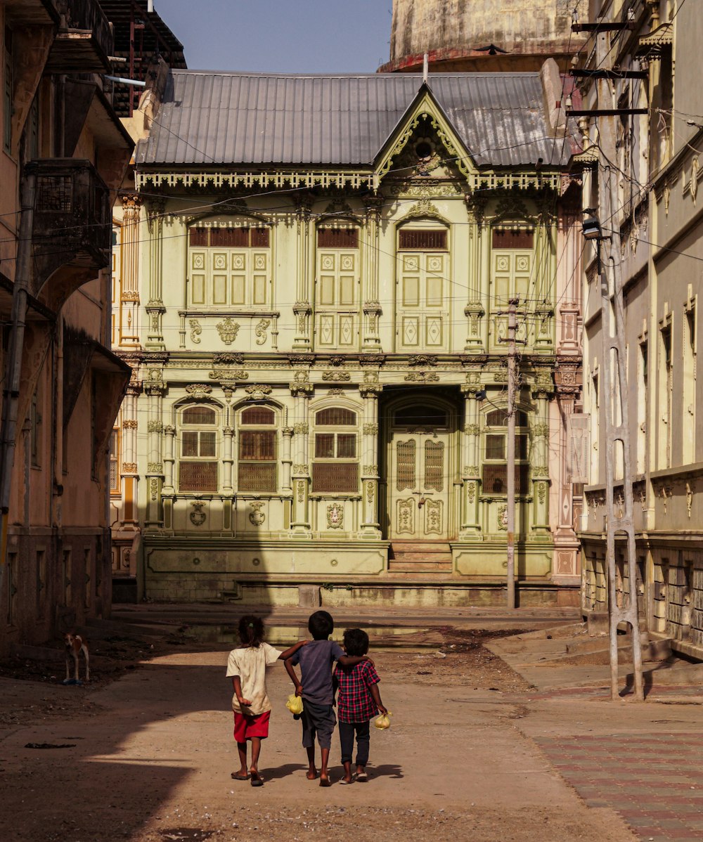 three children walking down a street in front of an old building