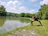 A serene morning scene with a person practicing yoga by a calm lake under a clear blue sky.