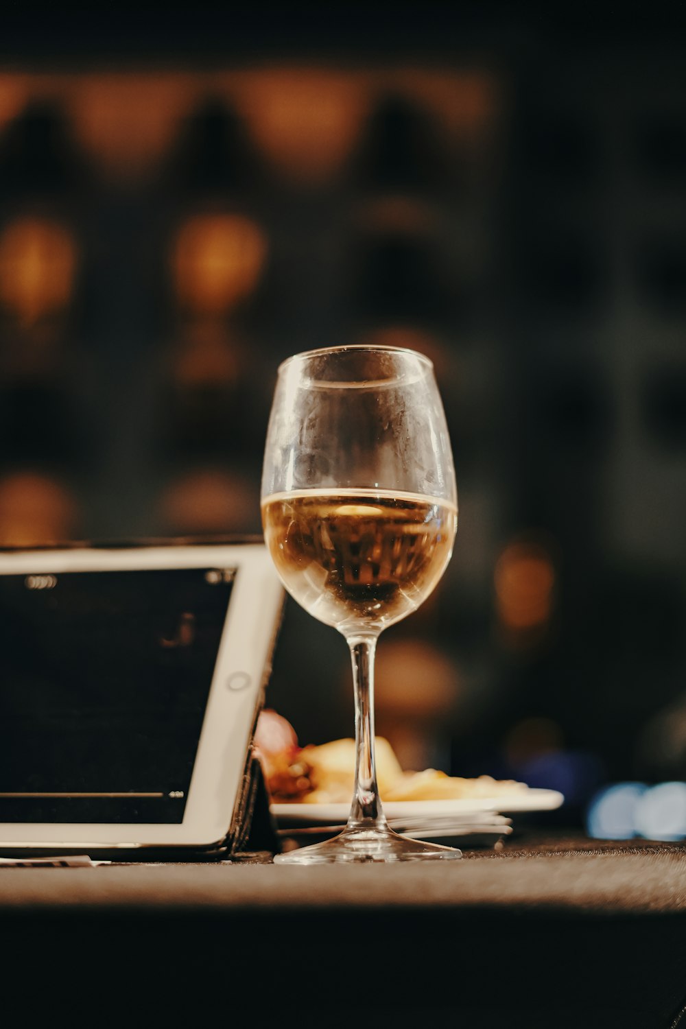 a glass of wine and a tablet on a table