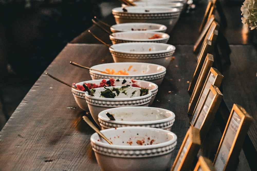 a row of white bowls sitting on top of a wooden table
