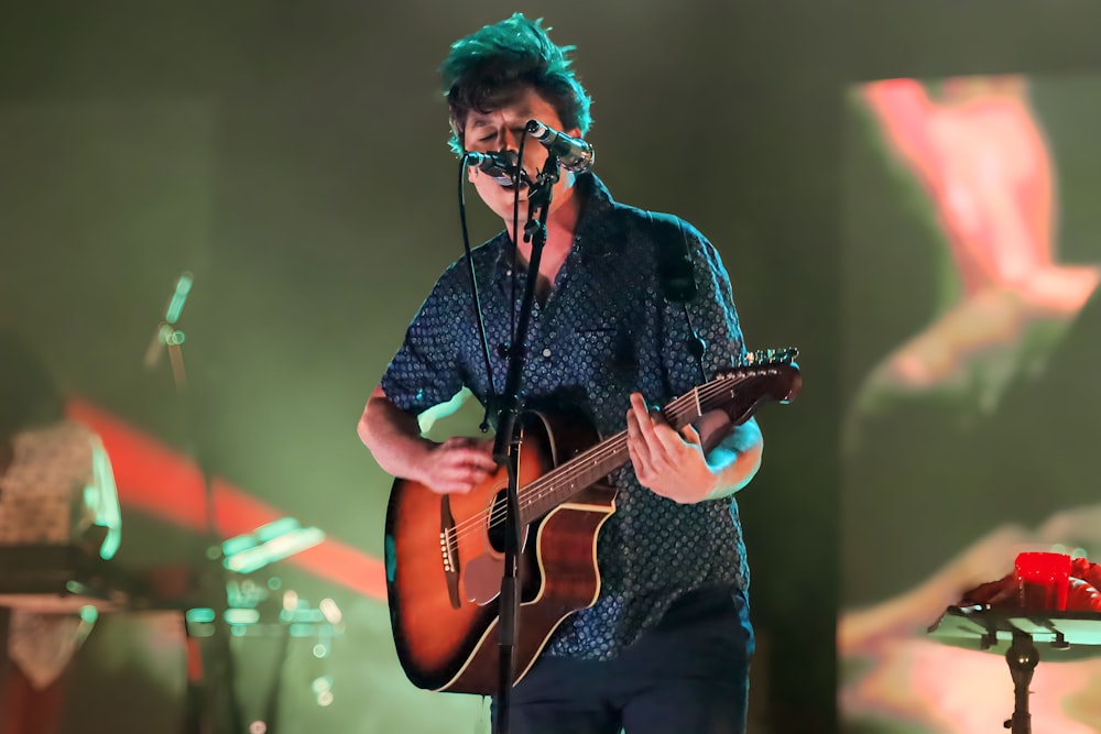 a man playing a guitar while singing into a microphone