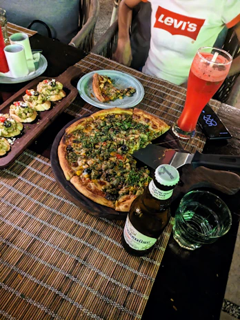 An inviting table setting with a variety of pizzas and a cold drink in a cozy restaurant ambiance