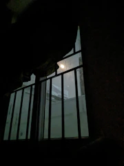 A hand passing commissary money through prison bars with soft light