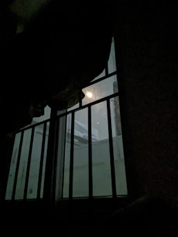 A hand passing commissary money through prison bars with soft light