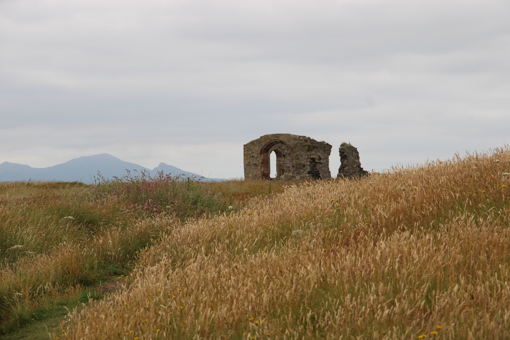 a stone building sitting on top of a grass covered hill