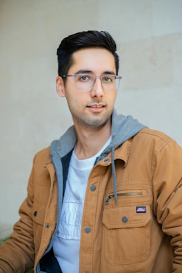 a man wearing glasses and a brown jacket