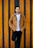 A stylish young man confidently wearing a minimalist brown jacket from Swag, standing against a cream-colored wall.