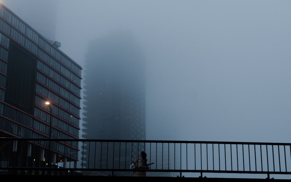 a person walking across a bridge in the fog