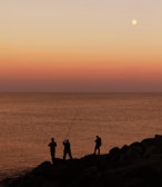 a couple of men standing on top of a rocky beach
