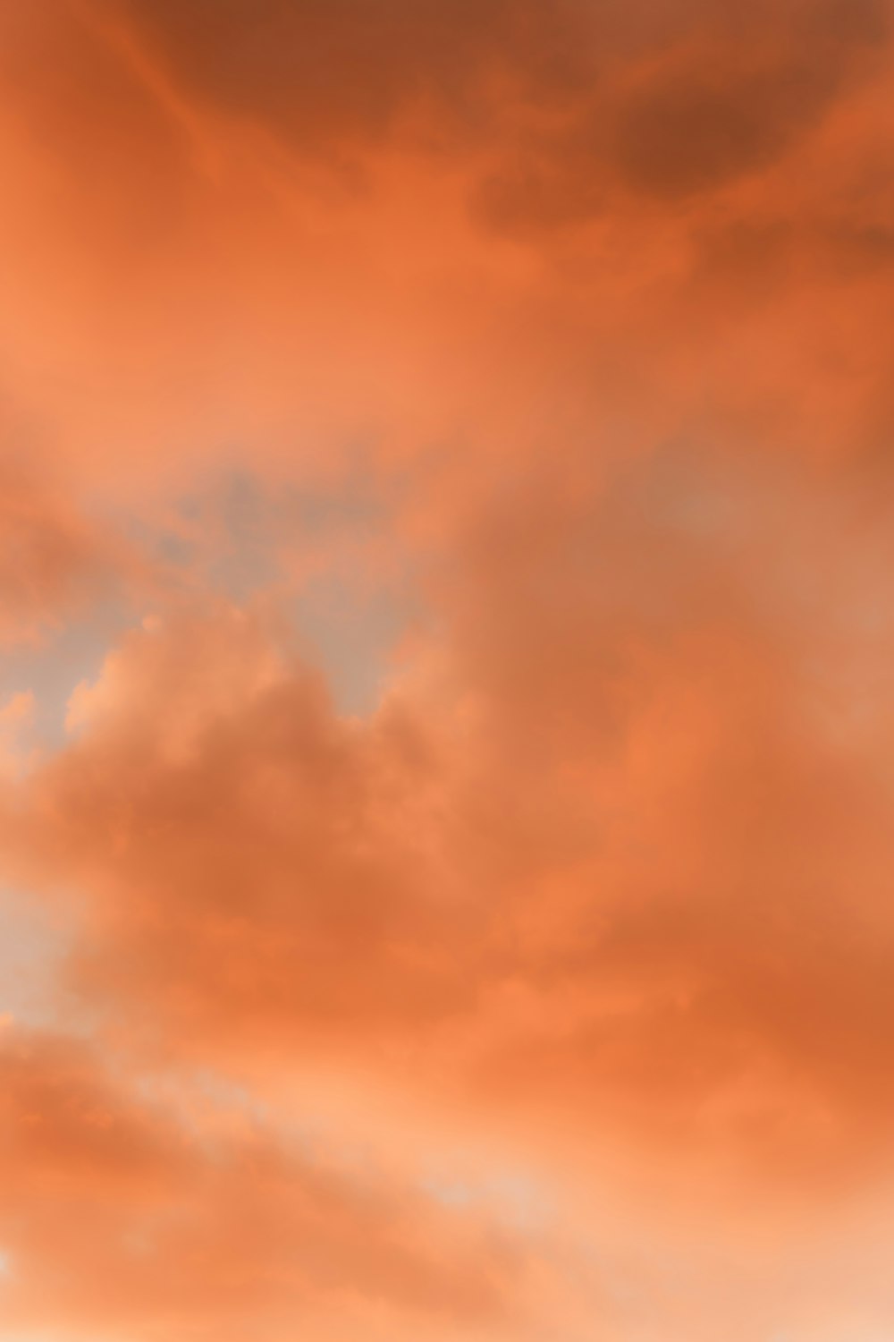 a plane flying through a cloudy sky at sunset