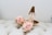 A pair of elegant high-heeled shoes with decorative rose-like embellishments at the toes, placed on a soft, tufted surface.