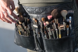 a person is holding a belt full of makeup brushes