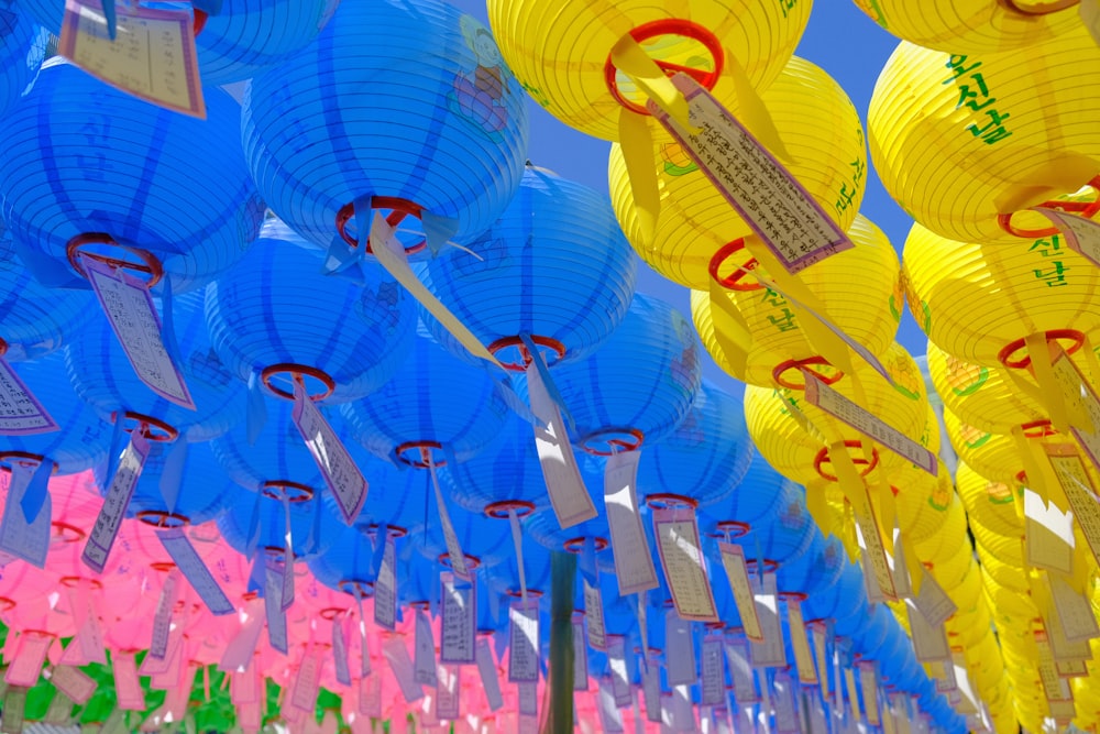 a row of yellow and blue lanterns hanging from the ceiling