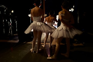 two ballerinas in white tutus standing in front of a mirror