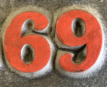 Bold red numbers 6 and 9 are prominently displayed against a textured gray background. The numbers appear to be embossed or raised, giving them a three-dimensional effect. There is a subtle shadow around the numbers, enhancing their visibility.